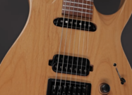Close-up of the Solar AB1.7ETN 7-string electric guitar showing natural wood finish, black pickups, fixed bridge, and control knob