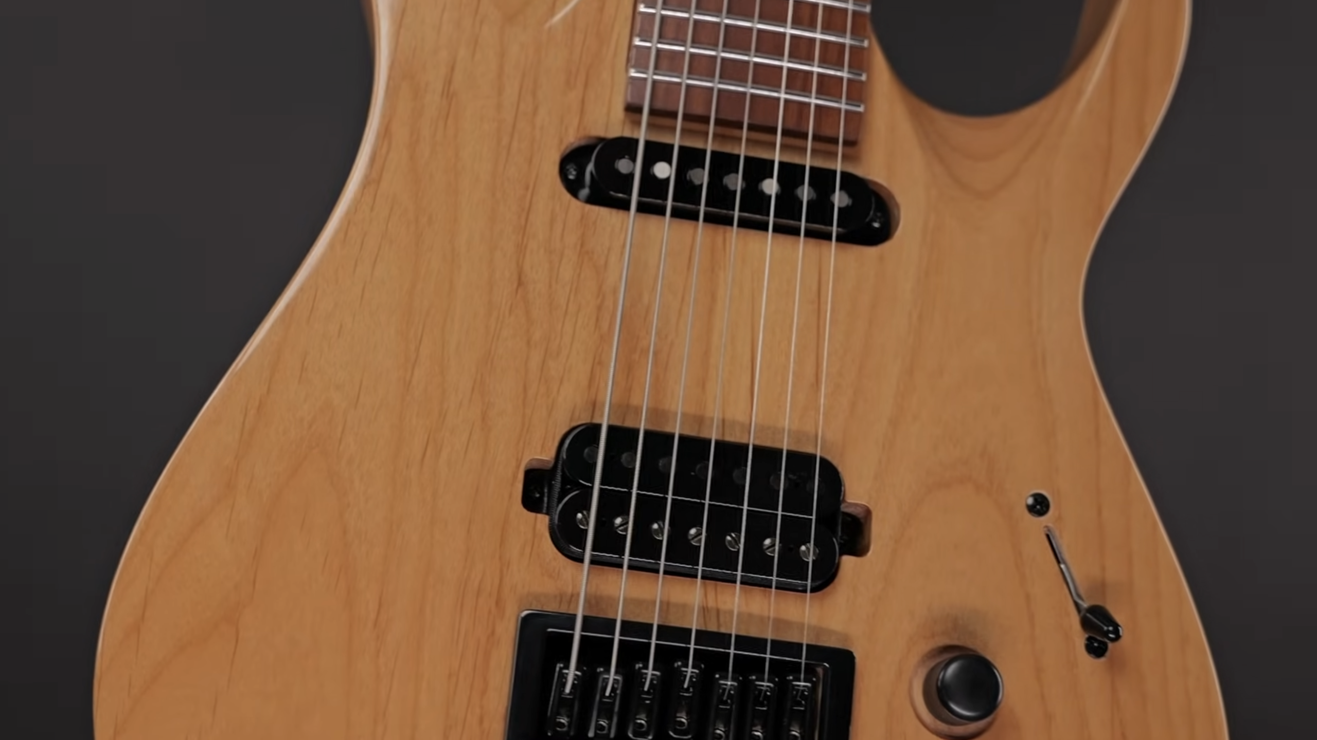 Close-up of the Solar AB1.7ETN 7-string electric guitar showing natural wood finish, black pickups, fixed bridge, and control knob