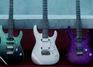 Three Jackson Pro Mod Plus Dinky DK24 electric guitars displayed side by side, featuring teal, white, and purple finishes against a textured wall background.