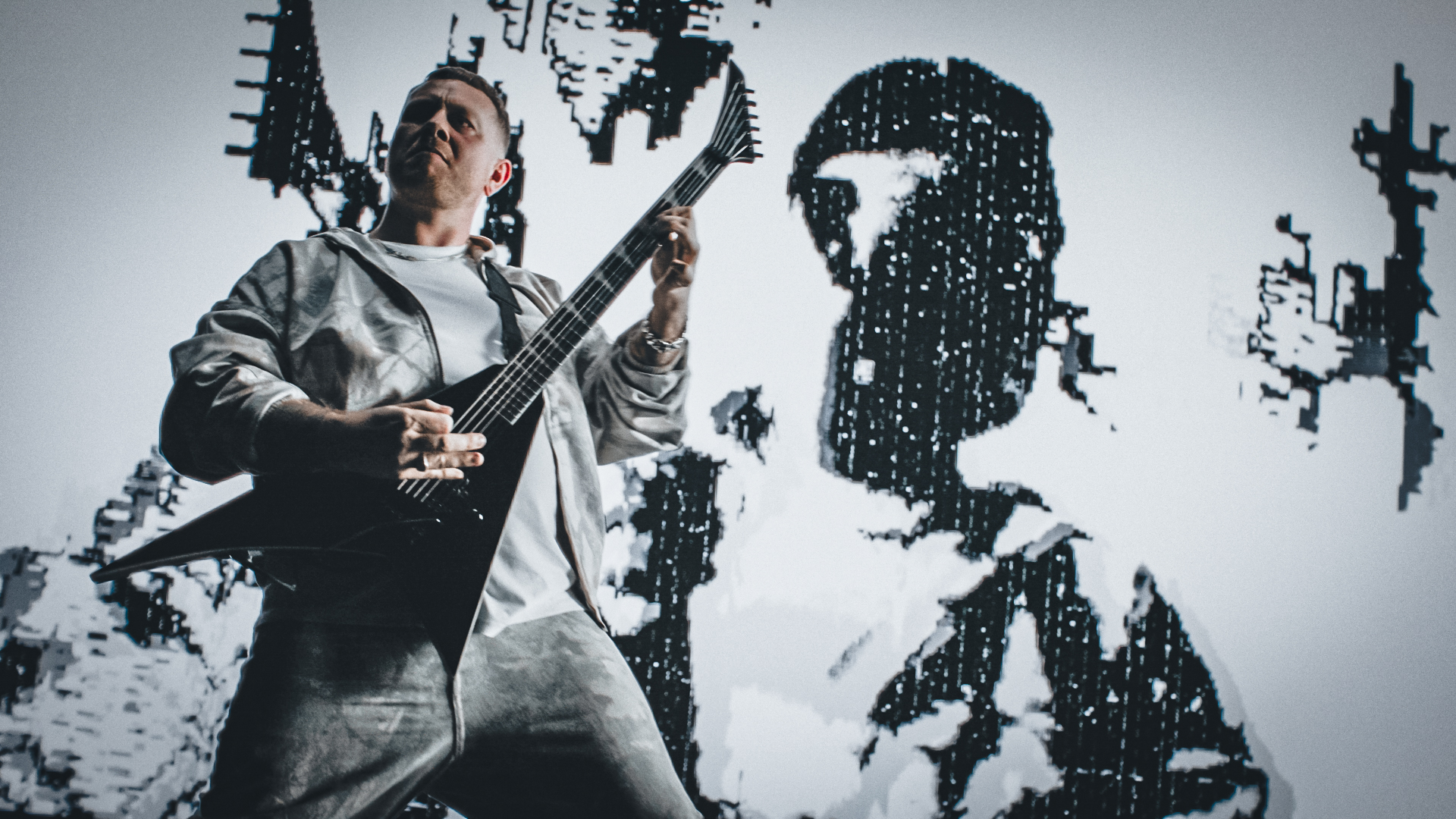 Musician performing with a satin black Jackson Pro Plus Pure Metal Stealth guitar onstage in front of a high-contrast digital backdrop