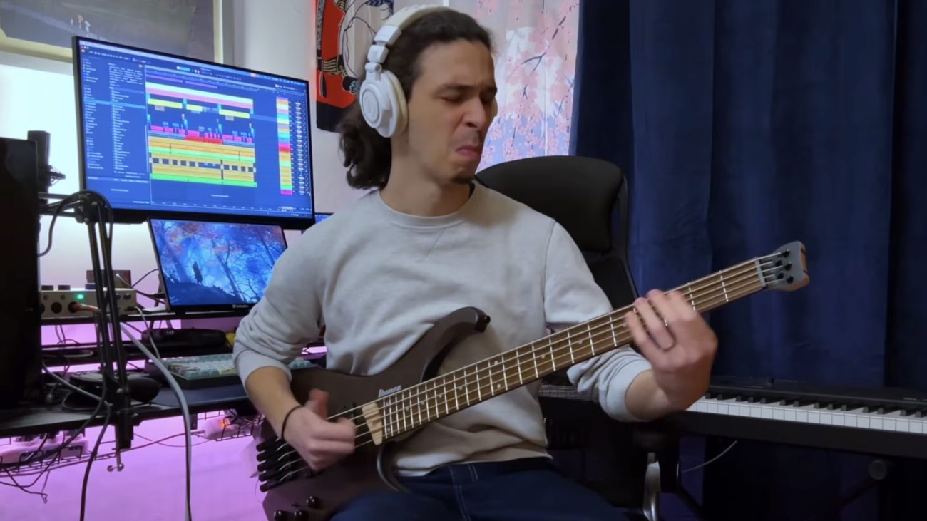 Riccardo Oliva playing an Ibanez EHB605 headless 5-string bass in a home studio setup.