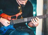 Guitarist playing an FM Guitars Masterline electric guitar during a performance or demo.