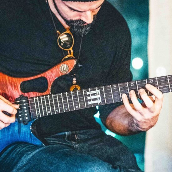 Guitarist playing an FM Guitars Masterline electric guitar during a performance or demo.