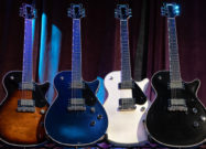 Four Gretsch Electromatic Premier Jet electric guitars in different finishes displayed on stands against a stage curtain backdrop.