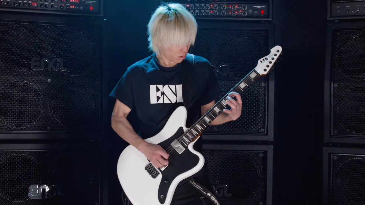 ESP LTD Deluxe XJ-2 HT in white finish played by guitarist onstage in front of stacked ENGL amplifier cabinets, showcasing the guitar’s aggressive offset body shape, reverse headstock, and high-performance modern metal design.