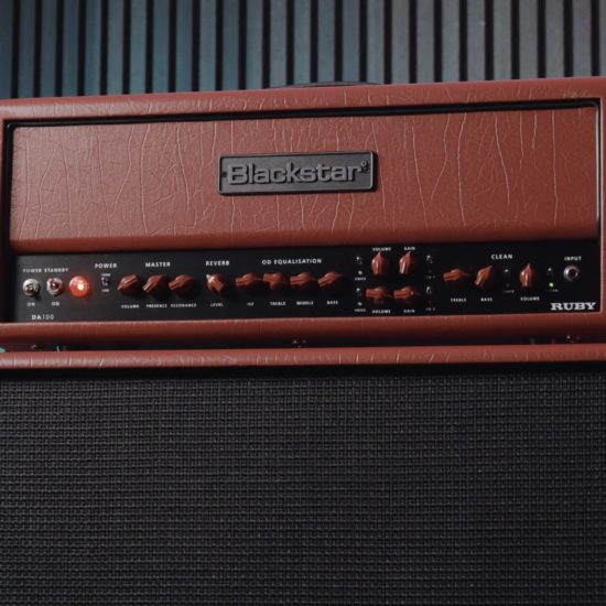 Close-up of the Blackstar DA100 Ruby Doug Aldrich signature 100-watt guitar amplifier head sitting on top of a matching DA412B speaker cabinet with red covering and black grille cloth.