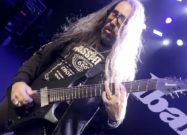 Julian Barrett playing an Ibanez ALPHA 8-string A528 electric guitar on stage under blue concert lights.