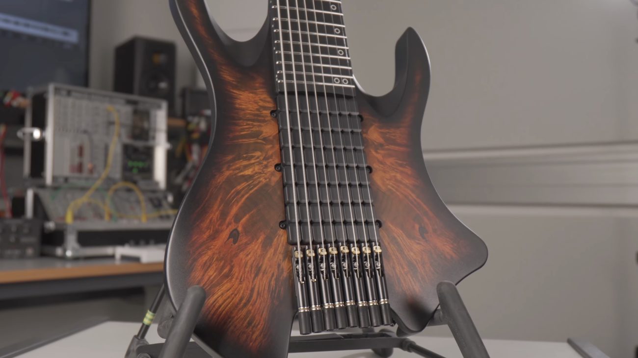 Close-up of a PolyMap electric guitar with a multi-scale fretboard and a dark burst finish, resting on a stand.