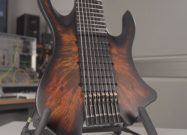 Close-up of a PolyMap electric guitar with a multi-scale fretboard and a dark burst finish, resting on a stand.