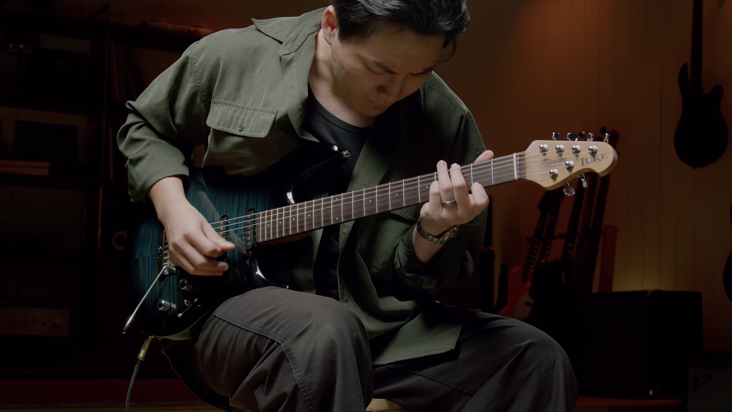 A photo of David Kim demoing the Sterling By Music Man Luke HSS guitar