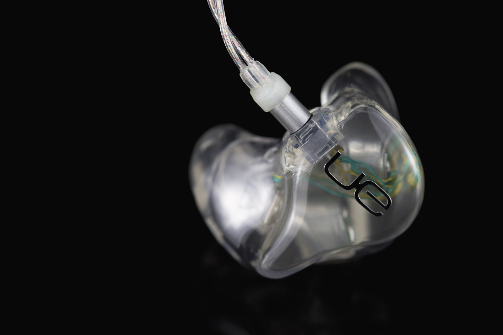 Clear-shell Ultimate Ears custom in-ear monitor with the silver IPX connector and SuperBax cable attached (UE press photo, April 2018)